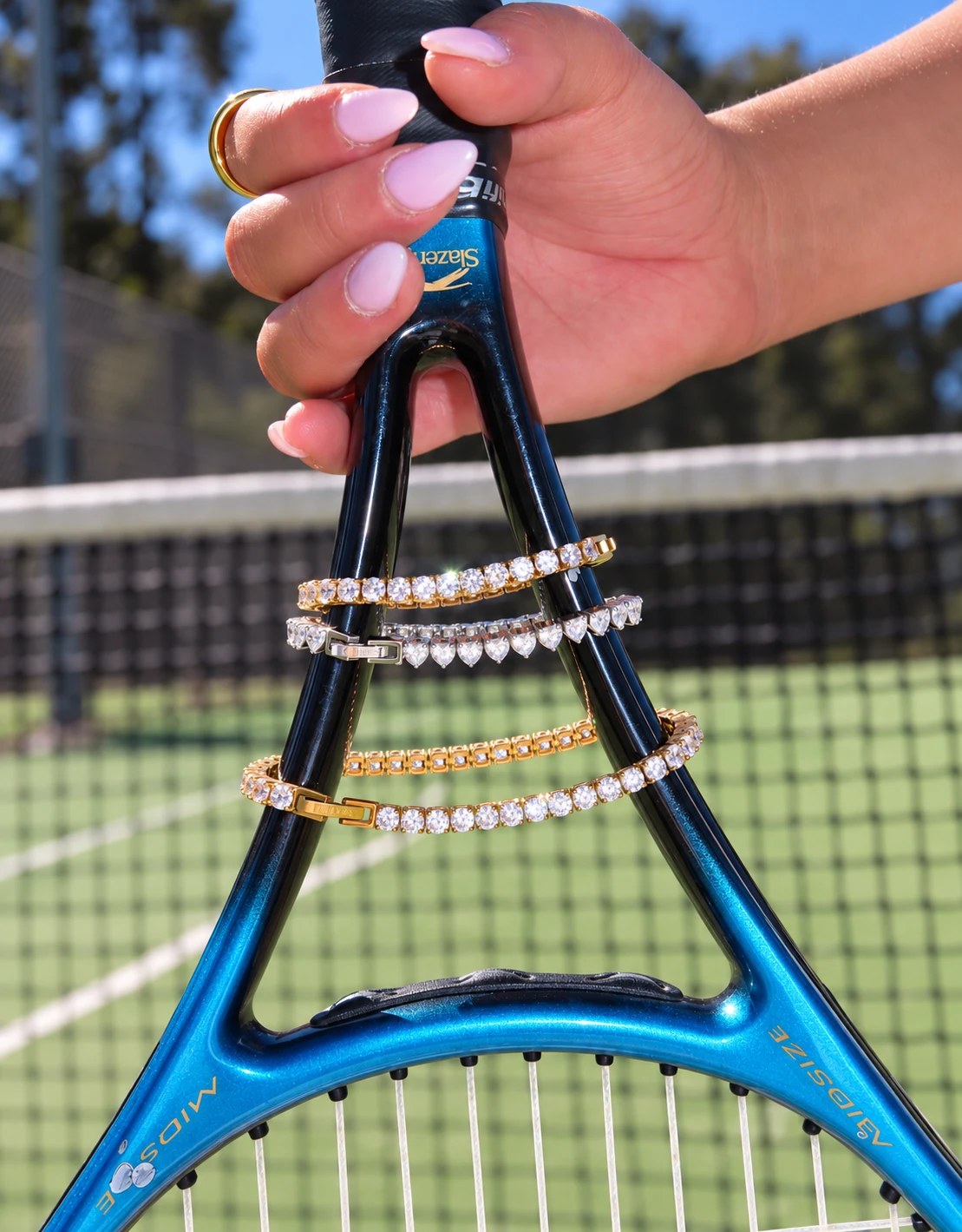 Gold and silver tennis bracelets on a tennis racket